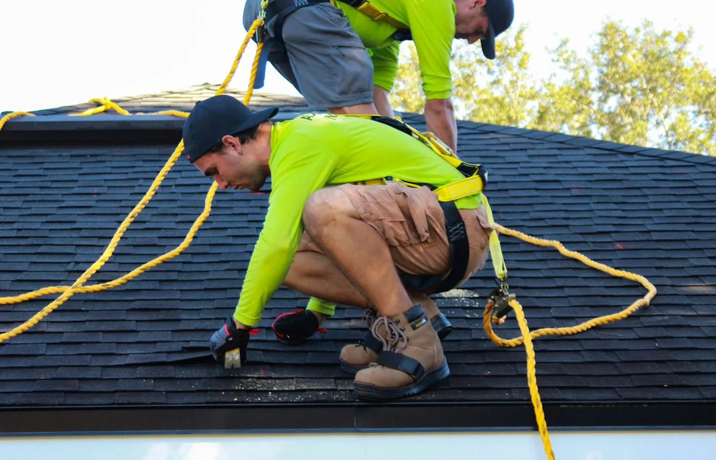 Roofer installing shingles on a suburban home